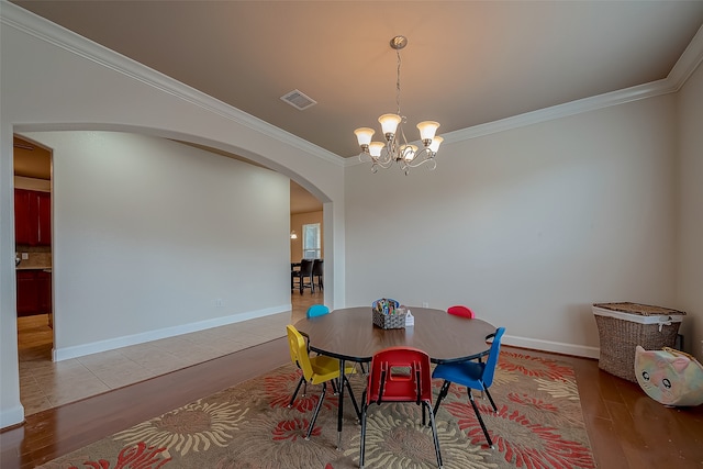 dining space with ornamental molding, a chandelier, and light hardwood / wood-style flooring