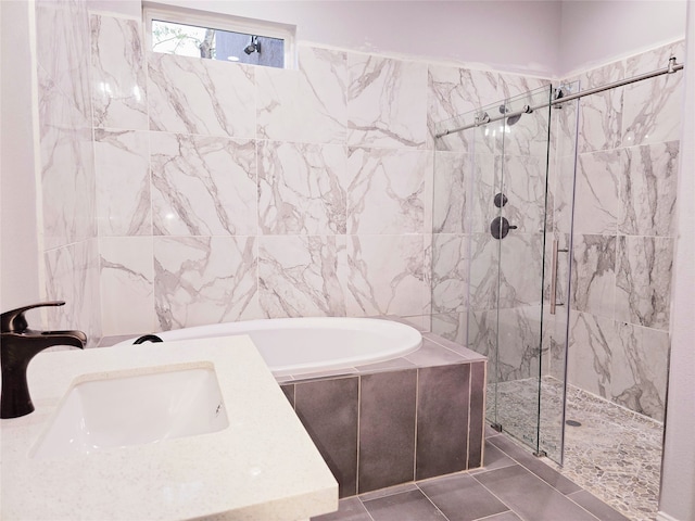 bathroom featuring tile patterned floors, tile walls, sink, and plus walk in shower