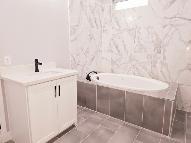 bathroom featuring tiled tub, vanity, tile walls, and tile patterned floors