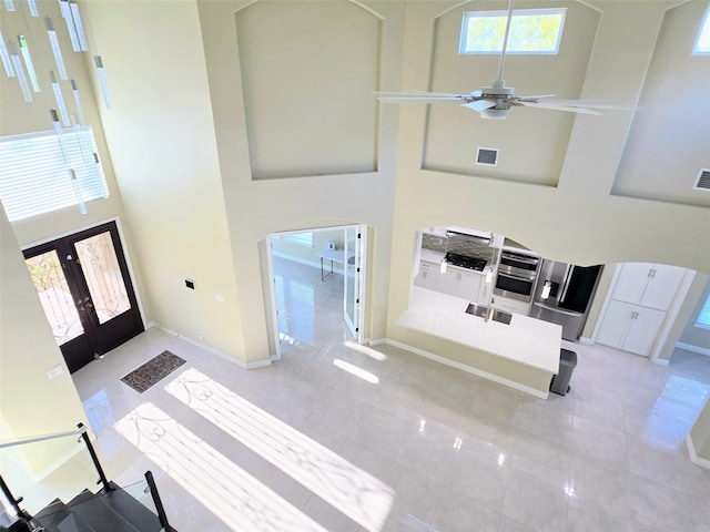 foyer featuring french doors, ceiling fan, a high ceiling, and a healthy amount of sunlight