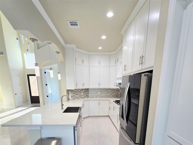 kitchen featuring backsplash, white cabinets, appliances with stainless steel finishes, and decorative light fixtures