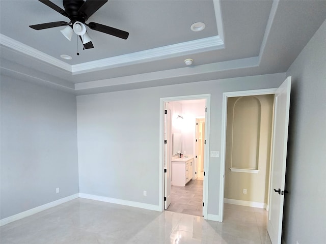 unfurnished bedroom featuring ceiling fan, a tray ceiling, crown molding, and ensuite bathroom