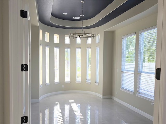 spare room with a raised ceiling and an inviting chandelier