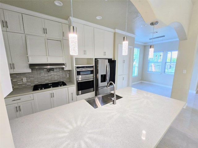 kitchen with tasteful backsplash, decorative light fixtures, ornamental molding, appliances with stainless steel finishes, and white cabinetry