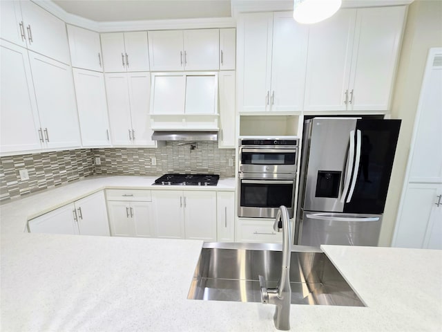 kitchen featuring light stone countertops, stainless steel appliances, backsplash, and white cabinetry