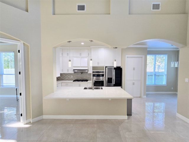 kitchen featuring pendant lighting, a wealth of natural light, white cabinetry, and stainless steel appliances