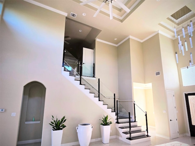 stairway with crown molding and a high ceiling