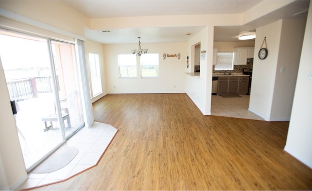 unfurnished living room with an inviting chandelier, light hardwood / wood-style flooring, and sink