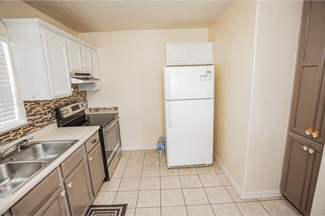 kitchen with light tile patterned flooring, a sink, freestanding refrigerator, backsplash, and electric range