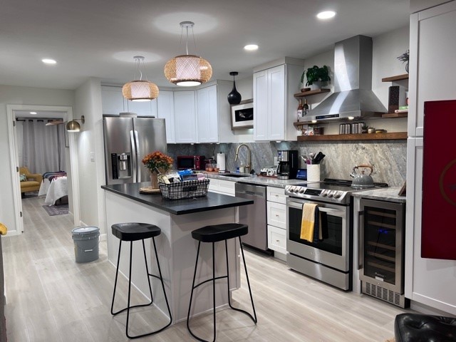 kitchen featuring stainless steel appliances, white cabinets, sink, island range hood, and a kitchen breakfast bar