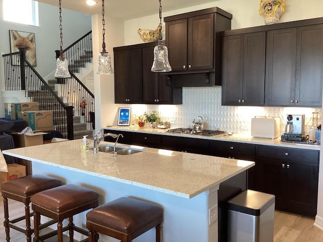 kitchen featuring light hardwood / wood-style flooring, a center island with sink, stainless steel gas stovetop, and sink