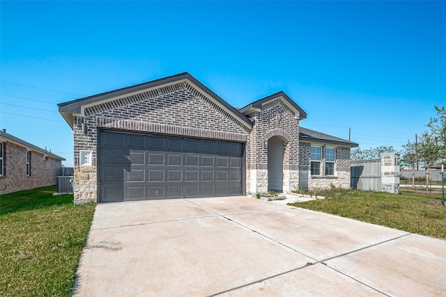 view of front of home with central air condition unit, a front yard, and a garage