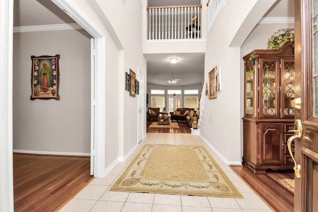 entrance foyer featuring ornamental molding, ceiling fan, a high ceiling, and light hardwood / wood-style flooring