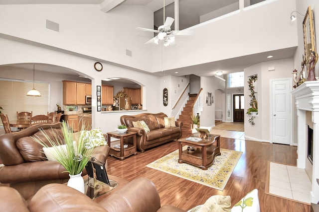 living room featuring beamed ceiling, high vaulted ceiling, ceiling fan, and light hardwood / wood-style floors