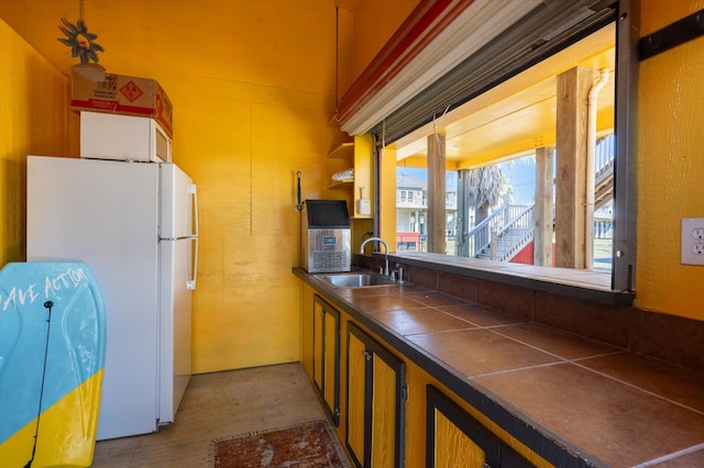 kitchen featuring white refrigerator, sink, and tile counters