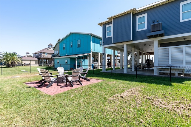 rear view of property featuring a fire pit, a lawn, and a patio