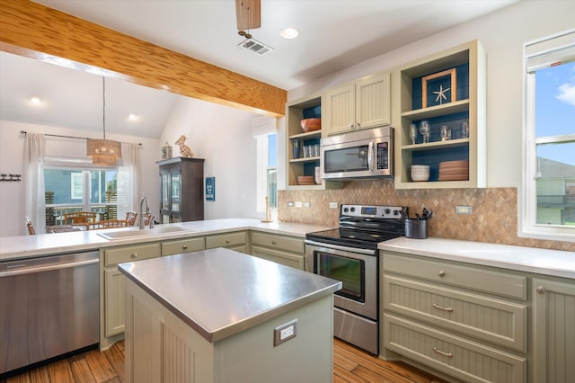 kitchen with a kitchen island, sink, pendant lighting, light hardwood / wood-style flooring, and appliances with stainless steel finishes