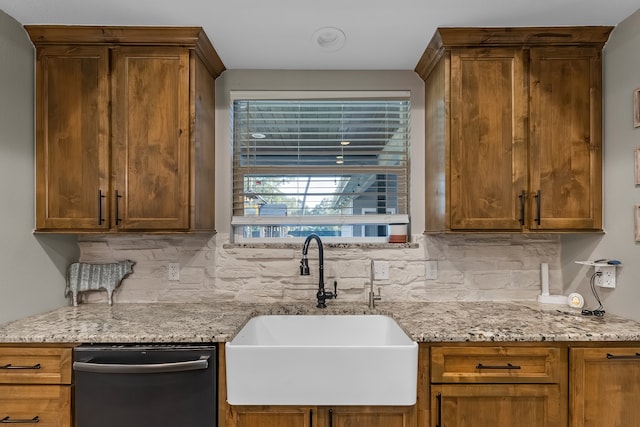 kitchen featuring dishwasher, decorative backsplash, light stone countertops, and sink