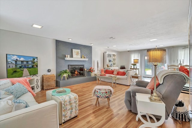 living room with a brick fireplace and light wood-type flooring