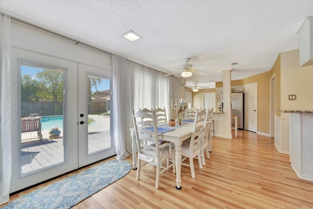 dining area with light wood-type flooring, ceiling fan, french doors, and a textured ceiling