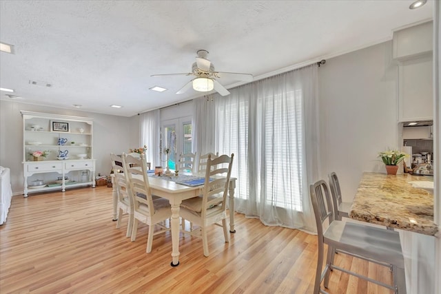 dining space with a textured ceiling, ceiling fan, and light hardwood / wood-style flooring