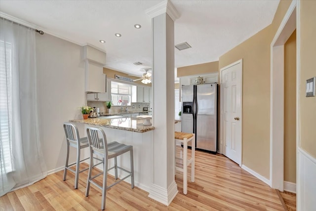 kitchen with light hardwood / wood-style flooring, white cabinets, and stainless steel fridge