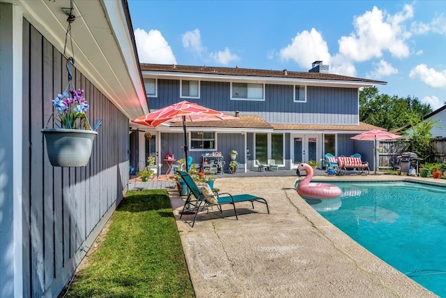 back of property with a fenced in pool and a patio area