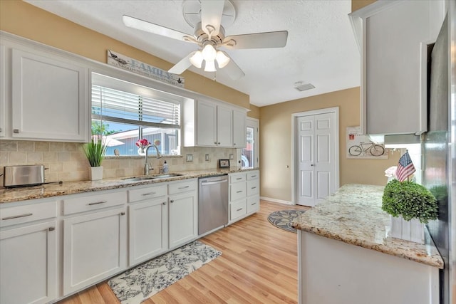 kitchen featuring light wood-type flooring, white cabinets, sink, and stainless steel dishwasher