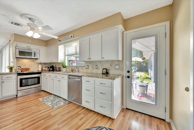 kitchen featuring stainless steel appliances, plenty of natural light, light hardwood / wood-style floors, and white cabinets