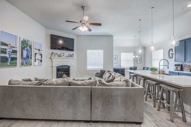 living room featuring light hardwood / wood-style floors, sink, and ceiling fan