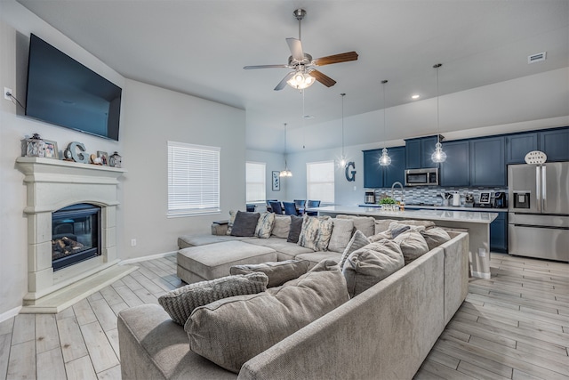 living room with ceiling fan, sink, and light hardwood / wood-style floors