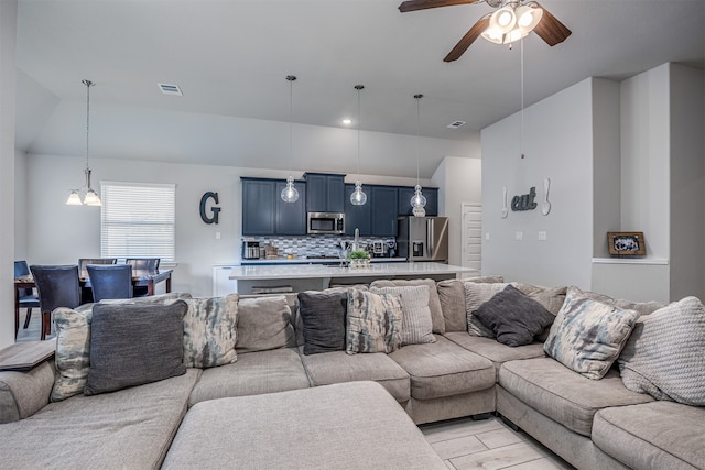 living room with ceiling fan with notable chandelier and light wood-type flooring