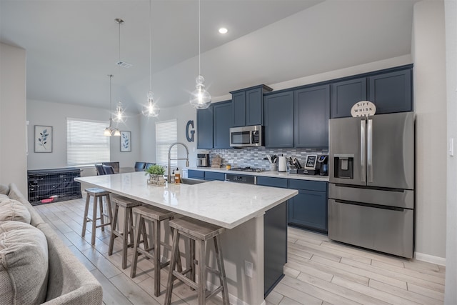 kitchen with hanging light fixtures, sink, a center island with sink, stainless steel appliances, and a breakfast bar