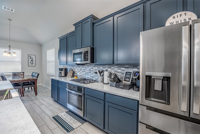 kitchen featuring hanging light fixtures, stainless steel appliances, light wood-type flooring, vaulted ceiling, and decorative backsplash