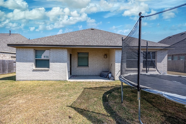 rear view of house featuring a trampoline, a patio area, and a lawn