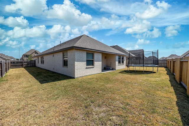 rear view of house with a trampoline and a yard