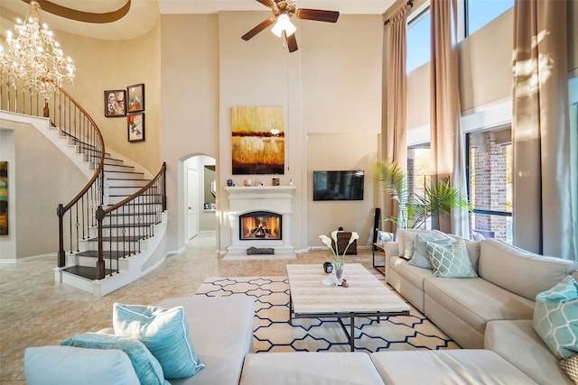 living room with a high ceiling and ceiling fan with notable chandelier