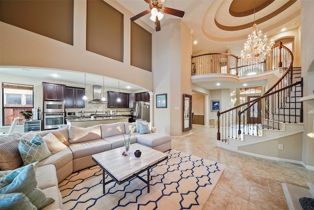 living room featuring sink, a towering ceiling, and ceiling fan with notable chandelier