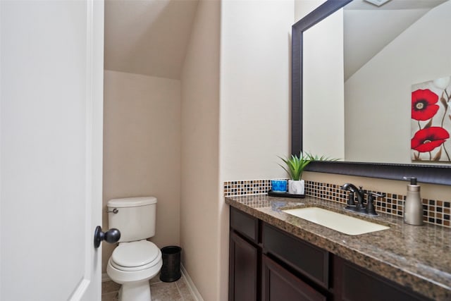 bathroom with tasteful backsplash, tile patterned floors, vaulted ceiling, toilet, and vanity