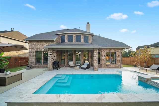 back of property with a fenced in pool and a patio area