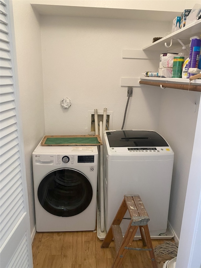 laundry room featuring washing machine and clothes dryer and hardwood / wood-style floors