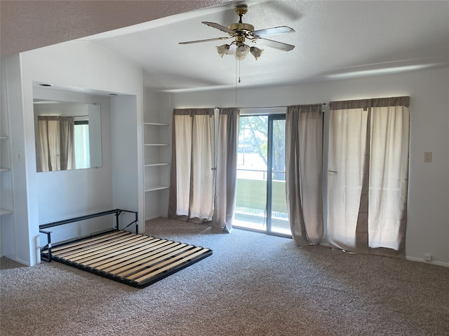 unfurnished bedroom with access to outside, a textured ceiling, carpet floors, ceiling fan, and vaulted ceiling