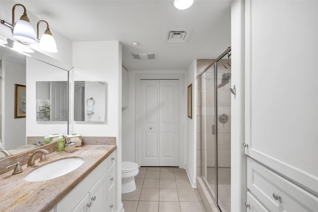 bathroom with vanity, a shower with shower door, tile patterned floors, and toilet