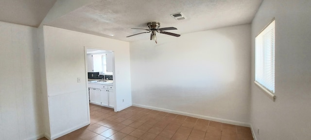 tiled spare room with ceiling fan, a textured ceiling, and sink