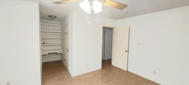 unfurnished bedroom with ceiling fan, a closet, and built in desk