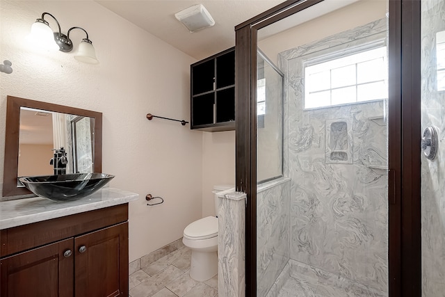 bathroom with tile patterned flooring, toilet, vanity, and tiled shower