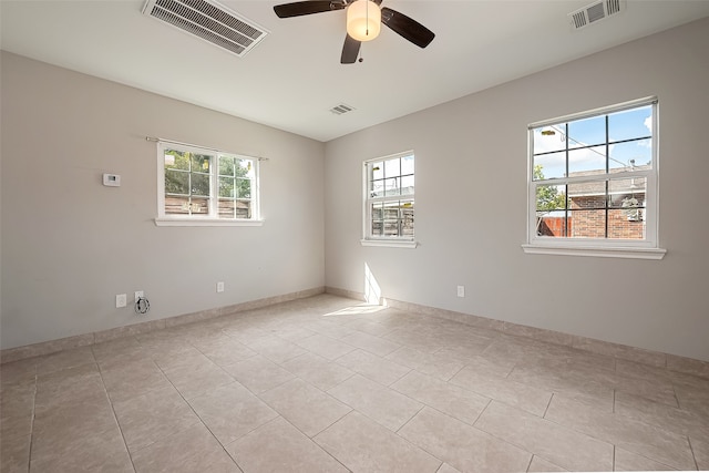 tiled empty room with ceiling fan and a wealth of natural light