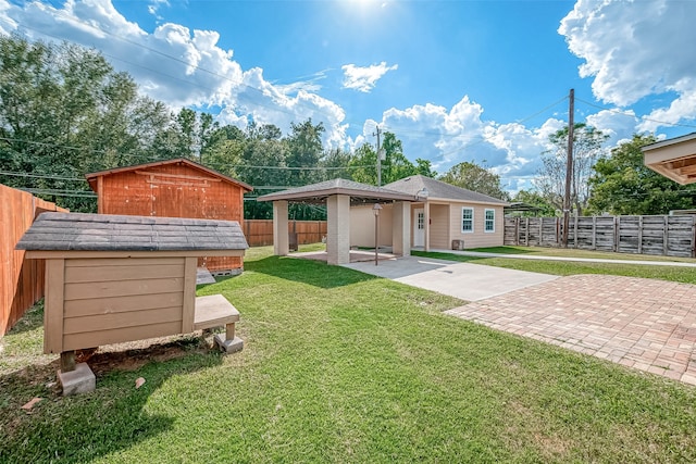 rear view of house featuring a yard, a storage unit, and a patio