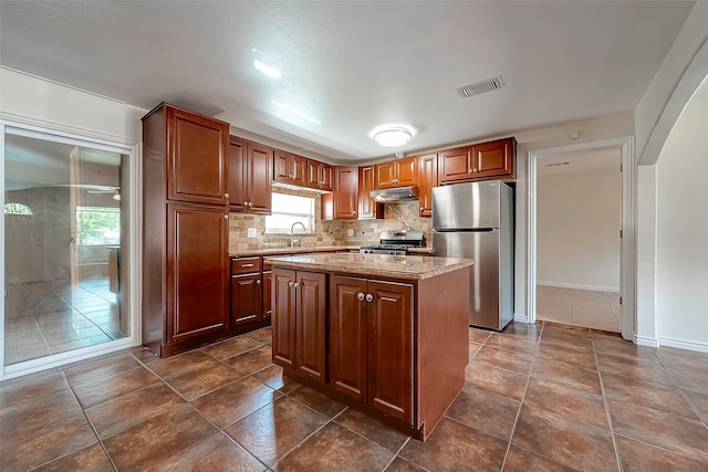 kitchen featuring dark tile patterned floors, light stone counters, decorative backsplash, a center island, and stainless steel appliances