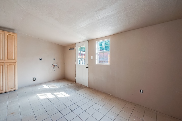 unfurnished room with a textured ceiling and light tile patterned flooring